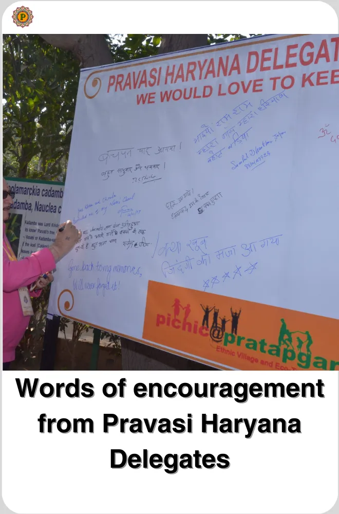 Woman in pink writing a message on a Pravasi Haryana Delegates signature board