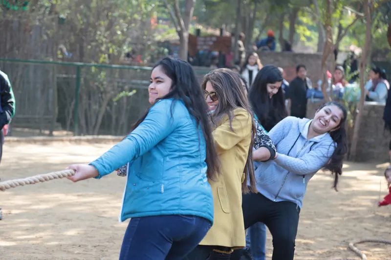 Women in winter jackets leaning back together to pull a thick rope in tug-of-war