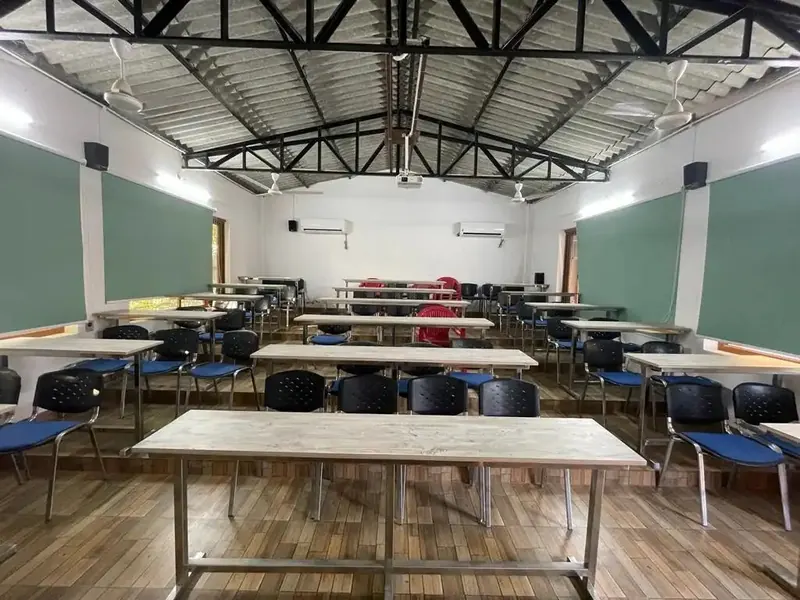 Air-conditioned training hall with tables, blue chairs and green notice boards