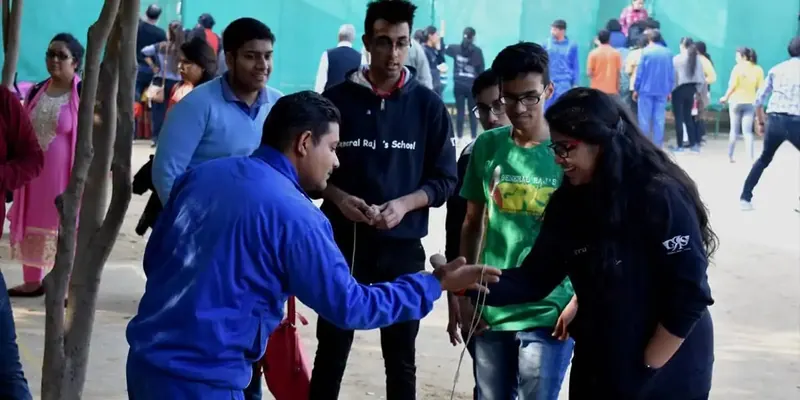 Man in blue guiding participants through a rope game in an open yard