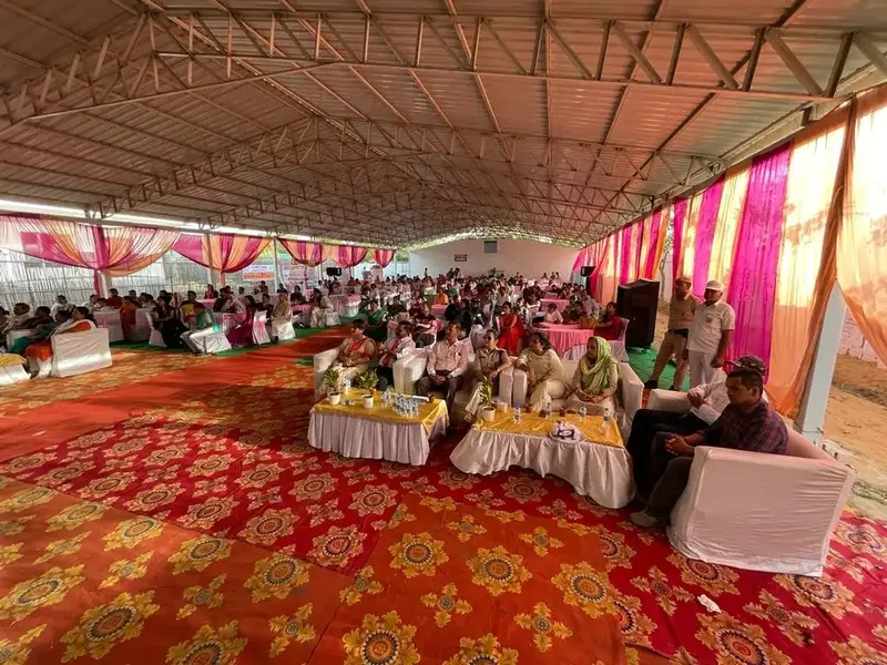 Decorated marquee with floral carpet and guests seated at tables under drapes