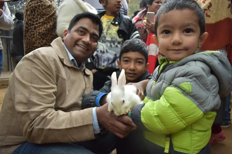 A father and two young children holding a white rabbit at Pratapgarh Farms