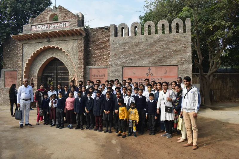Large school group posing before the brick arch and welcome sign at the farm entrance